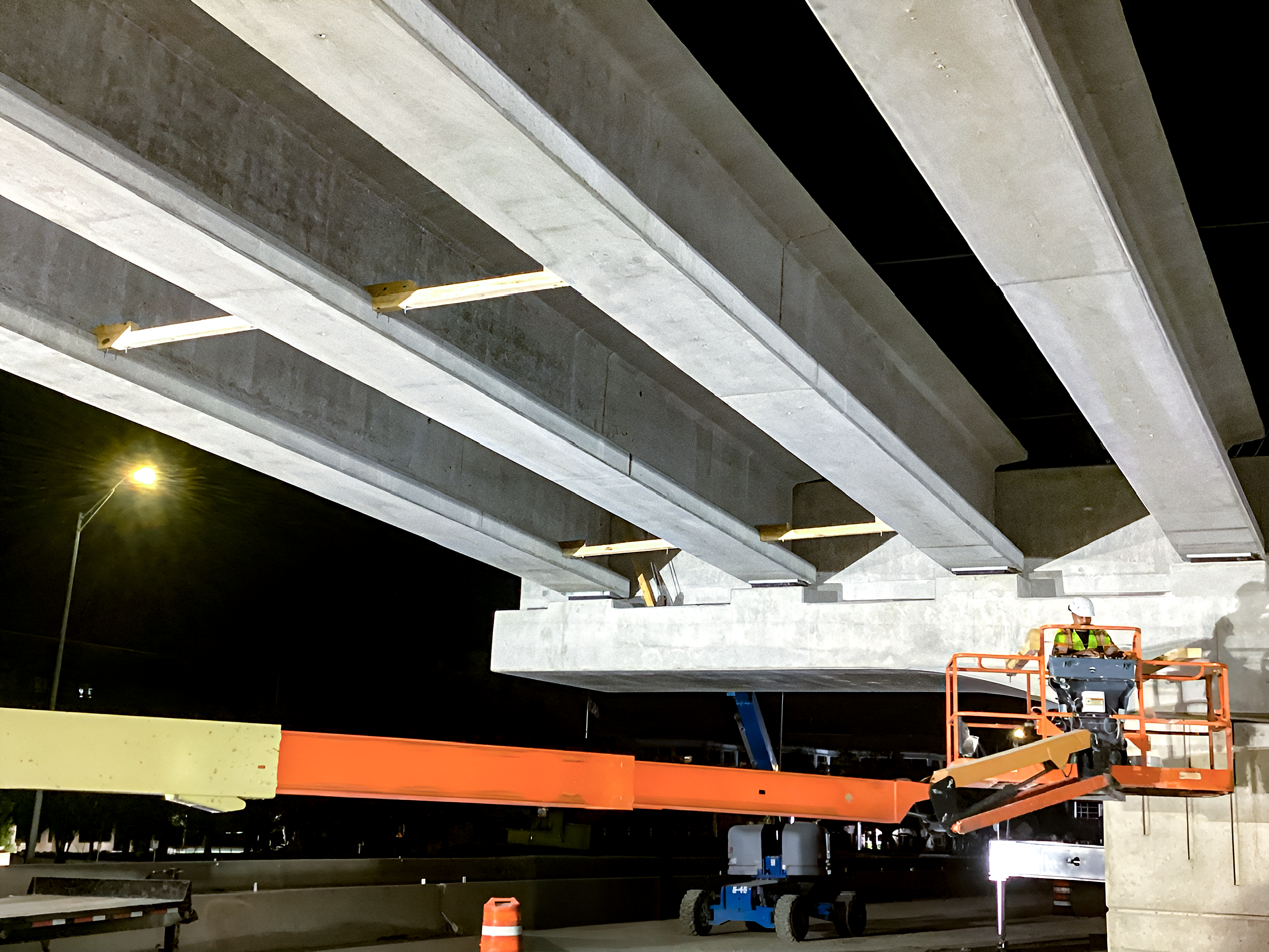 Nightime shot of crews placing girders on the outside bridge widening